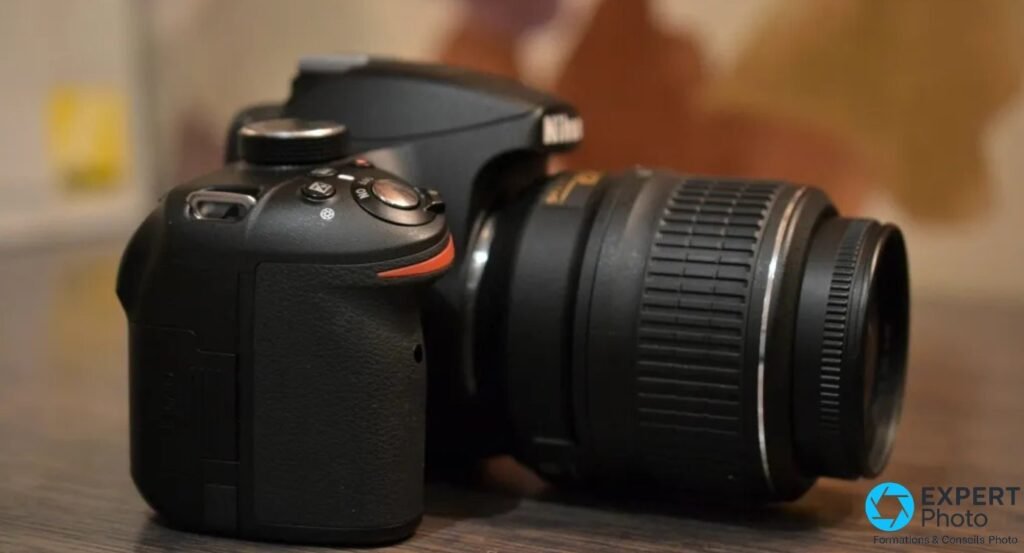 Nikon D3200 noir de profil droit, grip et molette du dessus, objectif 18-55mm avec bouchon avant monté