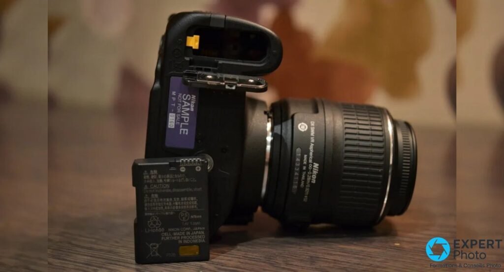 Nikon D3200 trappe batterie ouverte, batterie Nikon EN-EL14 Li-ion 7,4 V posée sur la table à côté