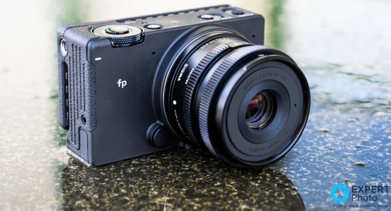 Sigma fp tenu en main, vue de dessus avec le Sigma 45mm f/2.8 DG DN — commandes CINE/STILL et bouton REC visibles