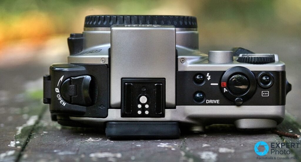 Canon EOS IX dessus, griffe flash, bouton OPEN trappe APS, bouton Drive et molette de commandes argentée