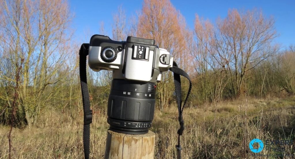 Canon EOS IX7 vu de dessus : griffe porte-flash Speedlite clairement visible, molette de modes et déclencheur, objectif Tamron