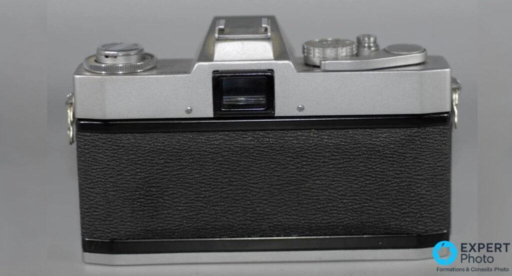 Canon EXEE vu de dos, boîtier fermé : oculaire du viseur centré, revêtement gaufré noir, bouton de rembobinage à gauche