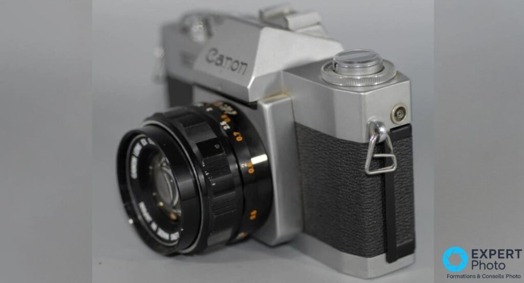 Canon EXEE vu de trois-quarts droite : prise PC de synchronisation flash, anneau de courroie, flanc argent et similicuir noir