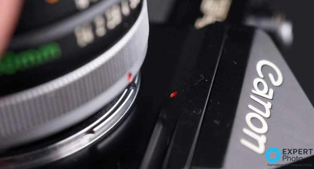 Gros plan monture Canon FD du F-1, point rouge d'alignement visible sur corps et bague objectif, inscription Canon sur pentaprisme