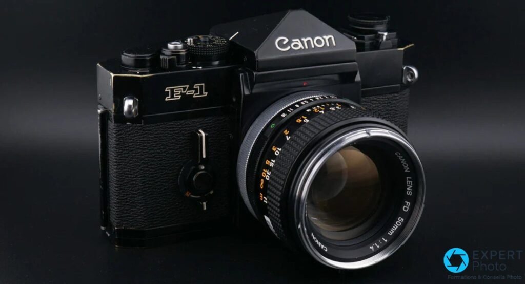 Canon F-1 noir face avant, inscription F-1 dorée visible, objectif Canon Lens FD 50mm 1:1.4 monté, fond sombre