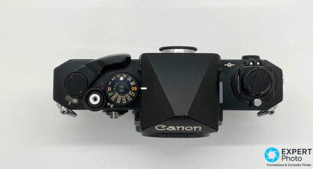 Canon F1N vu de dessus : molette de vitesses jusqu'à 1/2000e, levier d'armement et prisme avec logo Canon