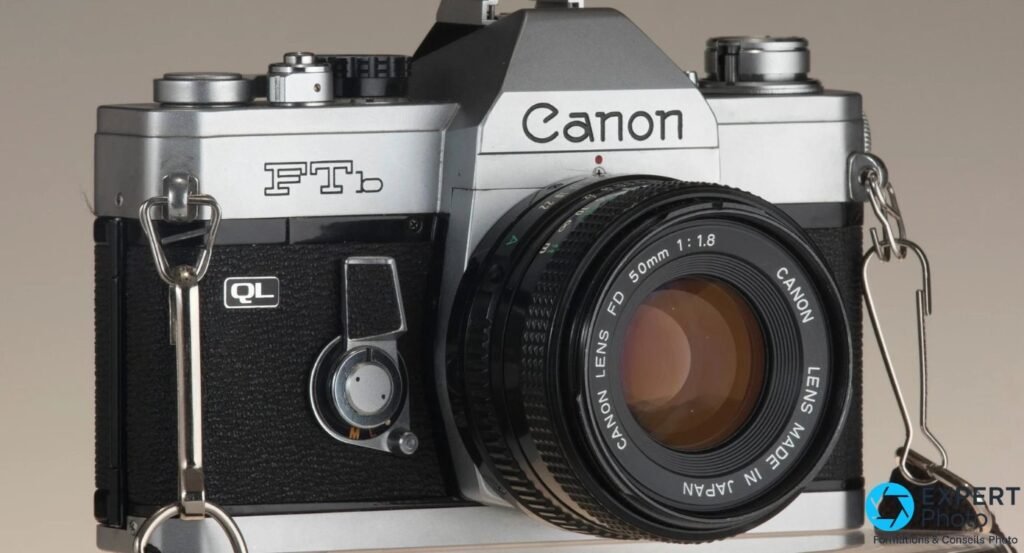 Canon FTb face avant : logos FTb et QL sur boîtier chromé, objectif FD 50mm 1:1.8 avec éléments frontaux visibles, fond gris