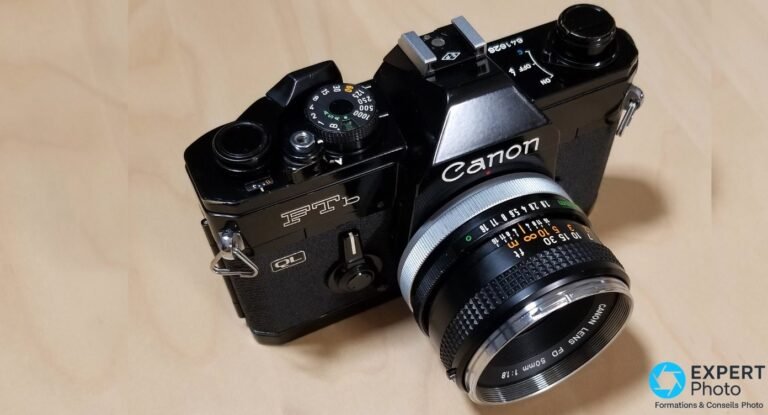 Canon FTb-N noir de trois quarts avant, Canon FD 50mm f/1.8 monté, molette vitesses et pentaprisme visibles