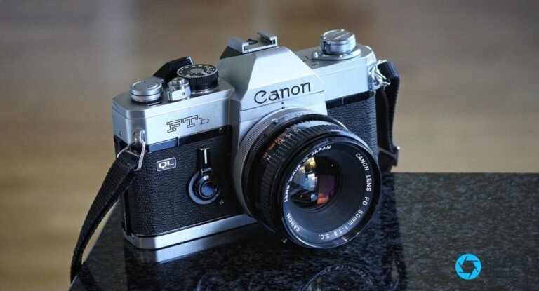 Canon FTb QL de trois quarts avant sur fond bokeh doré : objectif Canon FD 50mm 1:1.8 S.C., logo QL noir sur le grip