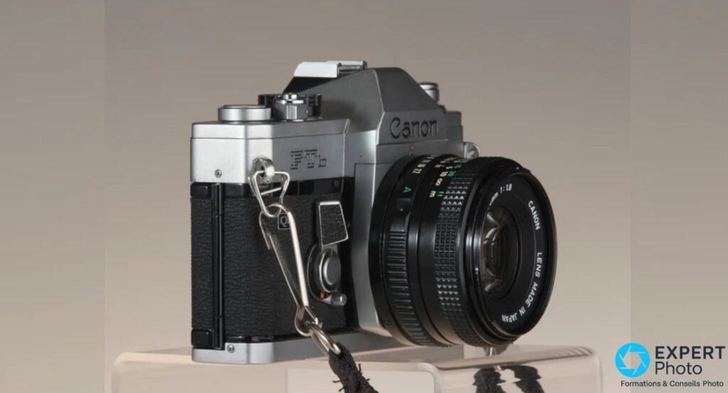 Canon FTb vu de trois quarts droit : inscription Canon FTb sur la face avant, objectif Canon FD 50mm f/1.8, fond neutre gris