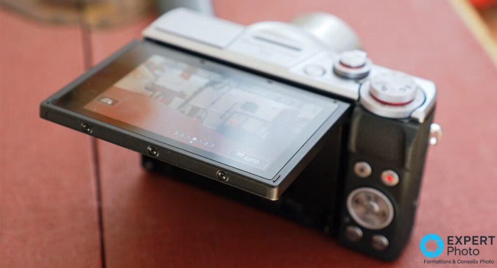 Main tenant un Canon G7X Mark III, vue du côté gauche montrant la prise USB et la prise micro 3,5 mm ouverte