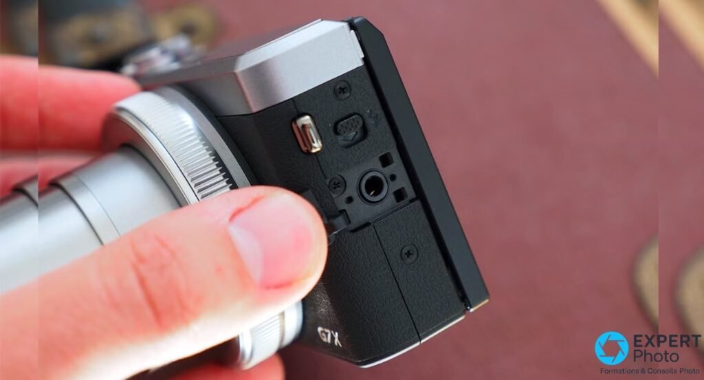 Canon G7X Mark III posé sur une table, écran relevé à 180° affichant le mode vidéo, micro visible en arrière-plan