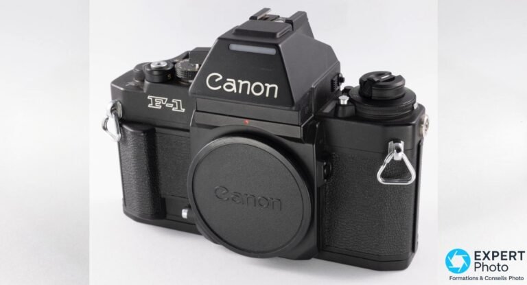 Canon New F-1 de face, boîtier noir mat, bouchon Canon, logo Canon sur le prisme, marquage F-1 et anneaux de courroie chromés