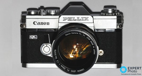  Canon Pellix QL vu de face sans objectif, miroir pelliculaire semi-transparent visible dans la chambre, levier stop-down a gauche 