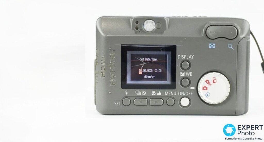 Canon PowerShot A10 vue de dos, écran LCD affichant menu Set Date/Time, molette modes, boutons DISPLAY WB et navigation. 