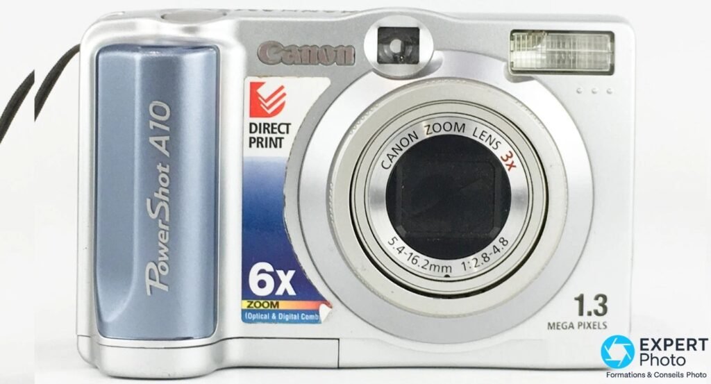 Canon PowerShot A10 face avant, objectif Canon Zoom Lens 3x, mention 1.3 Mega Pixels et Direct Print, fond blanc.