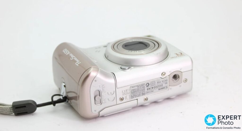 Canon PowerShot A510 vu de dessous, trappe du compartiment piles ouvrable, dragonne tressée, filetage trépied visible