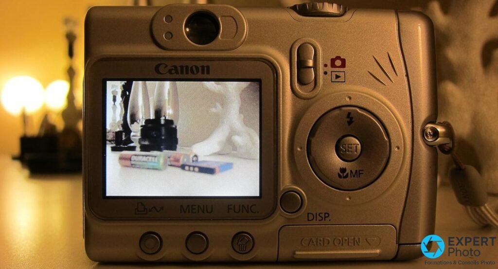 Canon PowerShot A520, face arrière, écran LCD 1,8 pouce allumé, boutons MENU FUNC SET MF, logo Canon, lumière chaude en fond 