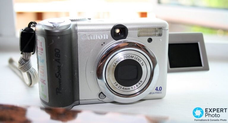 Canon PowerShot A80 face avant avec écran LCD orientable déplié sur le côté droit, fond fenêtre lumineuse