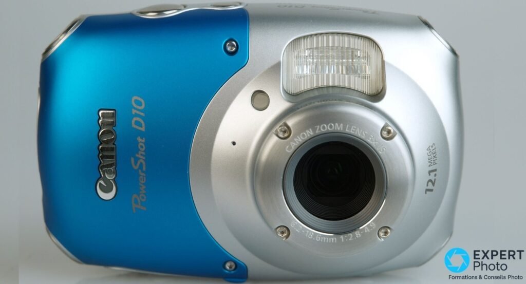 Canon PowerShot D10 bleu et argent, vue de face, objectif Canon Zoom Lens 3x IS, flash intégré, inscription 12.1 Mpx