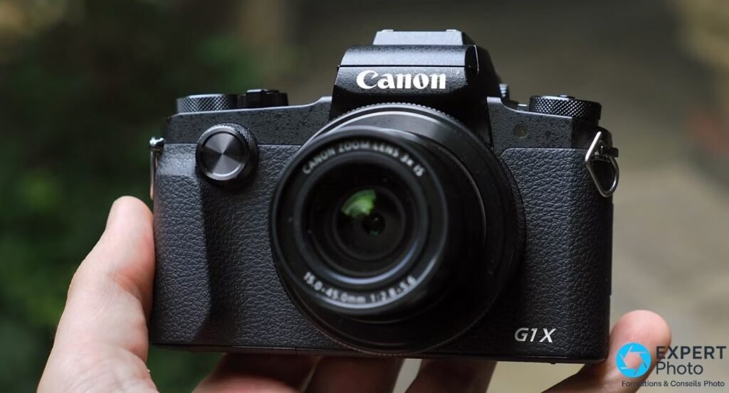 Canon PowerShot G1 X Mark III face avant tenu en main, objectif 15-45mm f/2.8, logos Canon et G1X bien lisibles sur boîtier noir