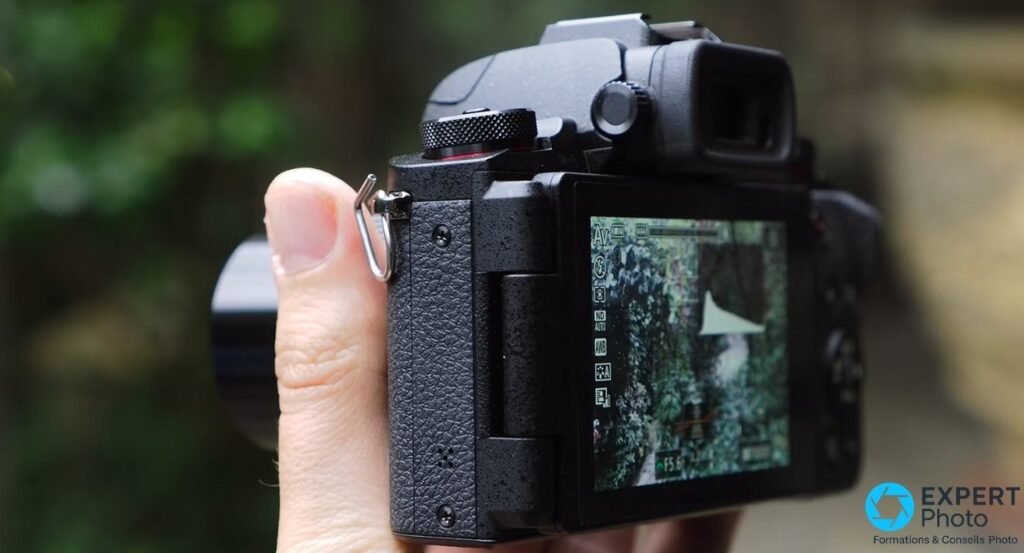 Canon PowerShot G1 X Mark III vu de profil gauche, main visible, écran tactile inclinable actif, anneau dragonne sur le flanc