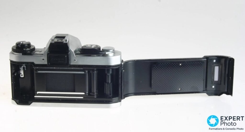 Fujica AX-1 trappe film ouverte : chambre, rails de guidage, rideau obturateur et logement bobine visibles