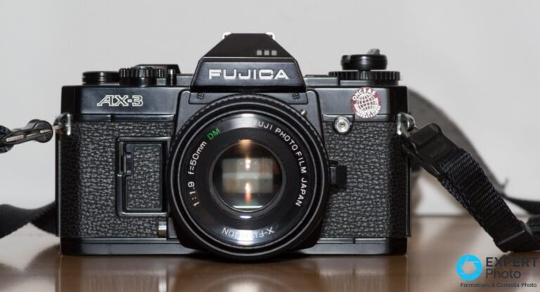 Fujica AX-3 noir face avant avec X-Fujinon 50mm f/1,9, inscriptions FUJICA et AX-3 lisibles, sangle noire