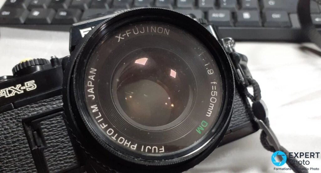 Objectif X-Fujinon 50mm f/1.9 DM monté sur Fujica AX-5 : inscription DM en vert, Fuji Photo Film Japan sur la bague