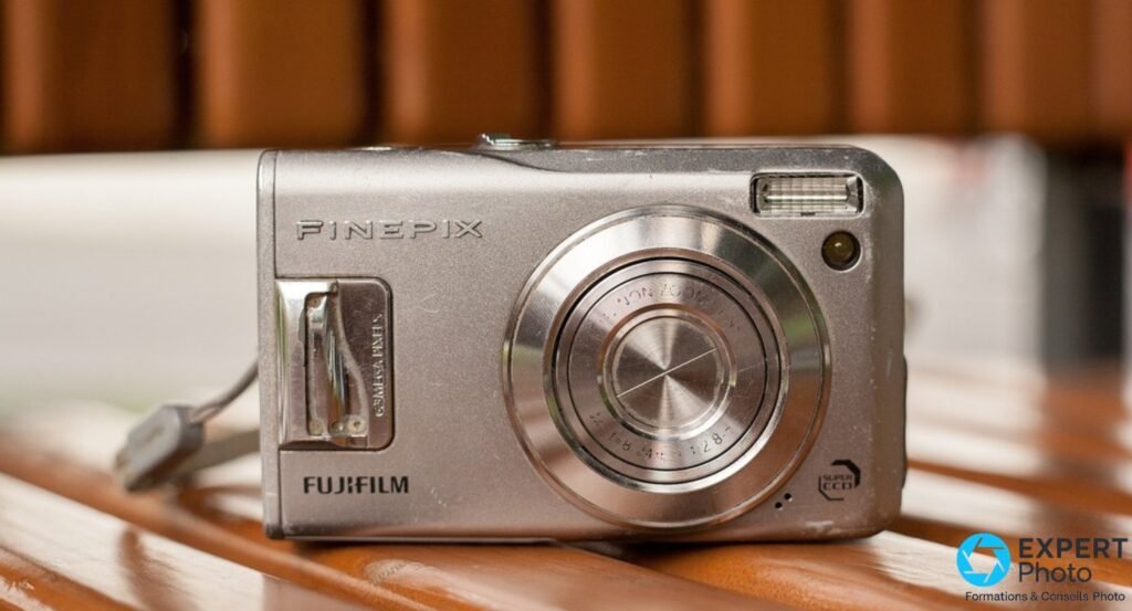 Fujifilm FinePix F31fd de face sur fond bois, logo FinePix, objectif Fujinon 3x zoom f/2,8, badge Super CCD 