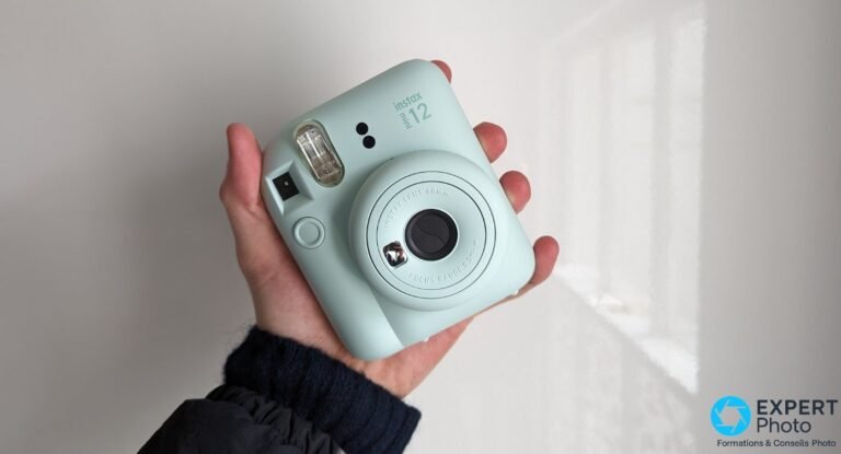 Test Fujifilm Instax Mini 12 : faut-il encore l’acheter avant le Mini 13 ? Fujifilm Instax Mini 12 vert menthe tenu en main, vue frontale avec flash, viseur et objectif visibles