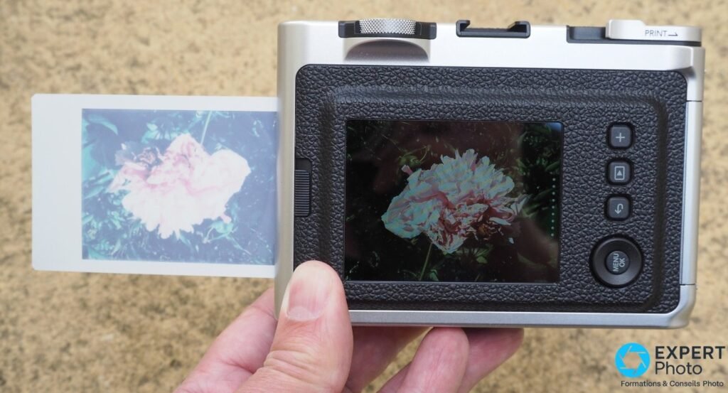 Dos du Fujifilm Instax Mini Evo, écran LCD affichant une pivoine rose avec effet, tirage Instax Mini développant à gauche