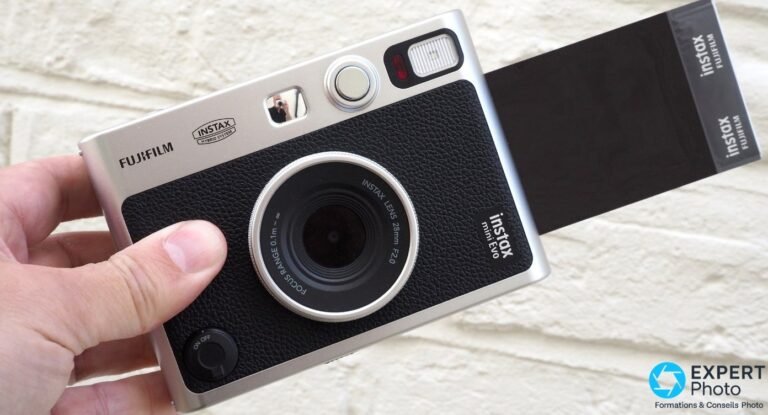 Main tenant le Fujifilm Instax Mini Evo de face, film Instax Mini noir en cours d'éjection sur le côté droit