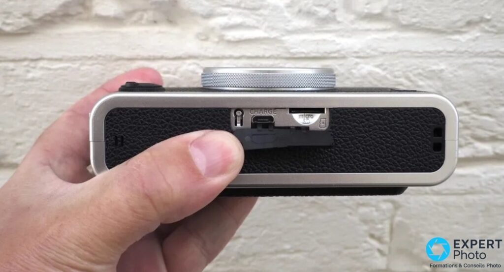 Tranche du Fujifilm Instax Mini Evo, cache ouvert révélant le port de charge micro-USB et la fente microSD