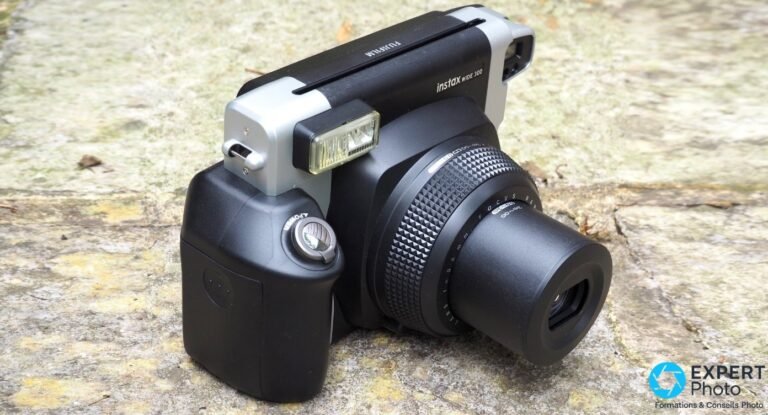Fujifilm Instax Wide 300 sur pierre, vue trois-quarts, flash levé, objectif 95mm et inscription instax WIDE 300 visibles