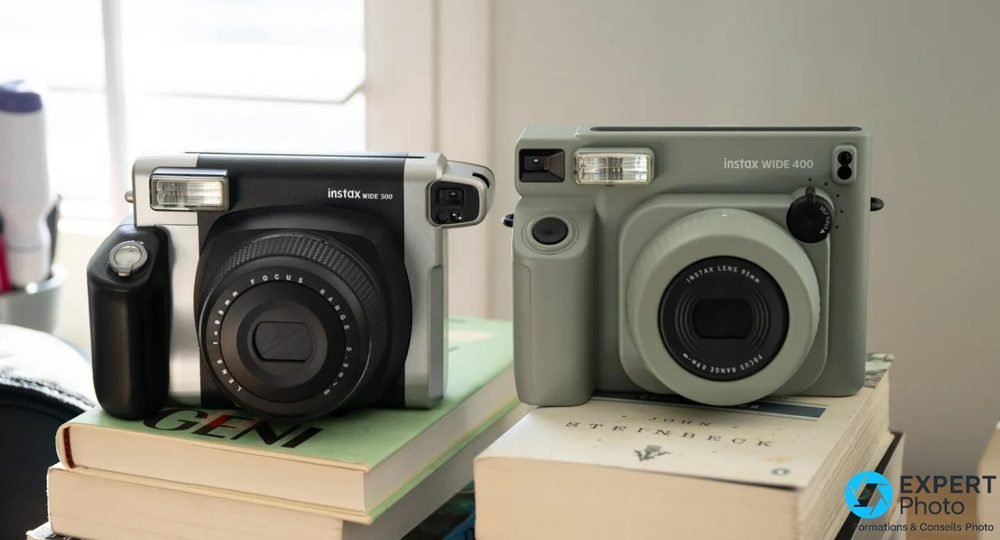 Instax Wide 300 noir à gauche et Wide 400 vert à droite, posés sur des livres, vus de face 