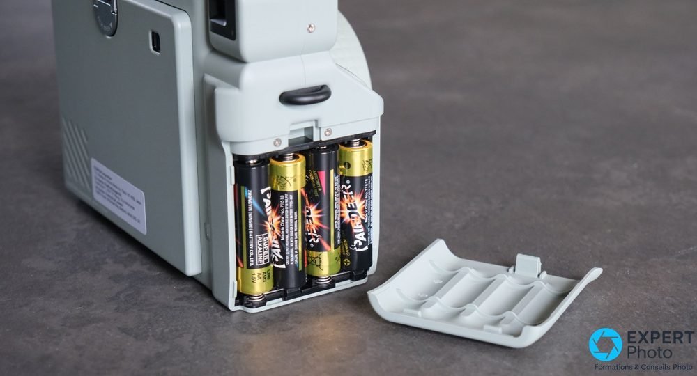 Dos de l'Instax Wide 400 vert, compartiment piles AA ouvert, quatre piles insérées, trappe à côté