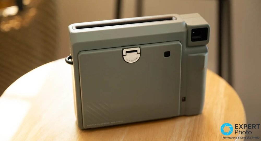 Dos de l'Instax Wide 400 vert sur table ronde, verrou FILM OPEN central et viseur carré en haut à droite