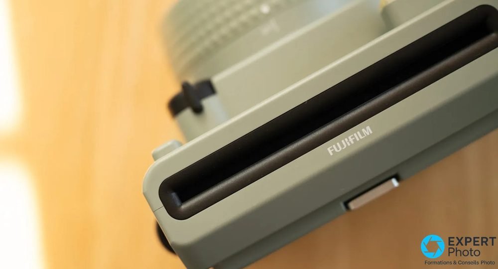 Gros plan sur la fente d'éjection de film de l'Instax Wide 400 vert, inscription FUJIFILM visible
