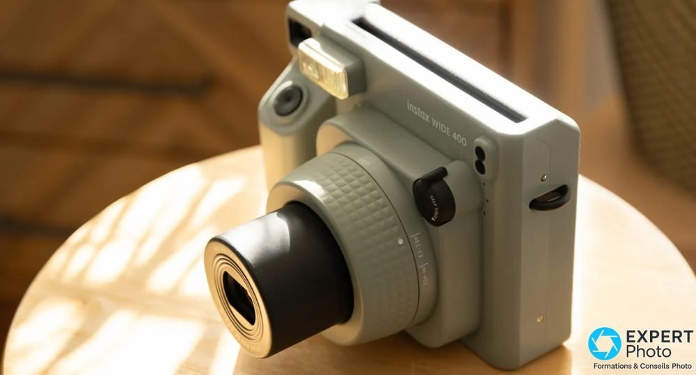Instax Wide 400 vert vue trois quarts, objectif déployé, fente d'éjection film en haut, flash allumé
