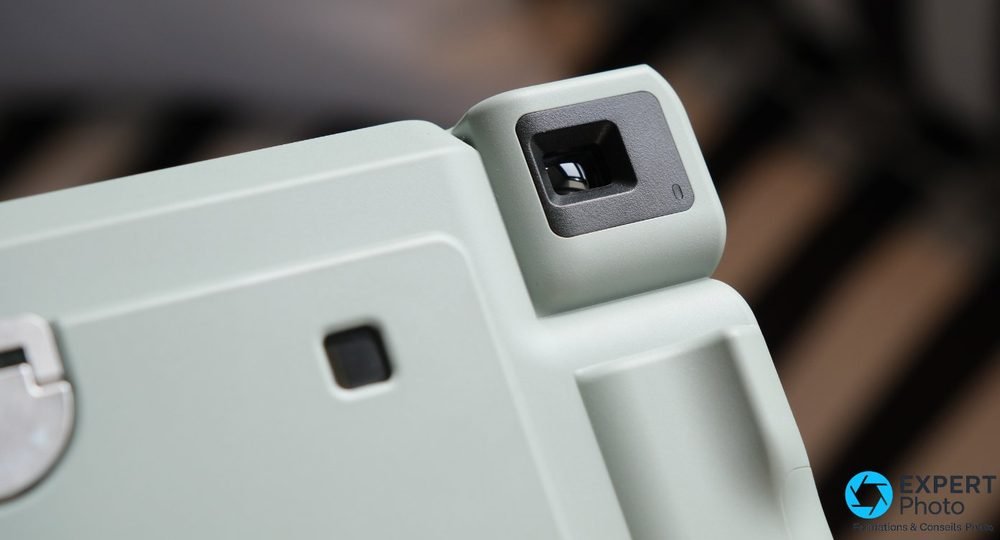 Gros plan sur le viseur optique carré de l'Instax Wide 400 vert, monture en saillie sur boîtier épuré