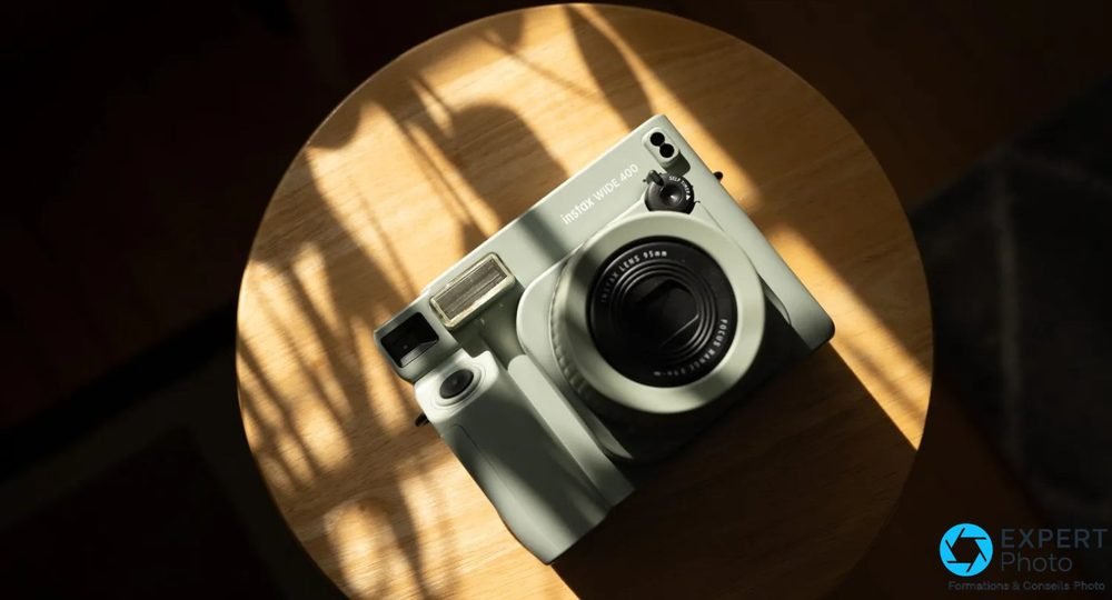 Instax Wide 400 vert posé sur table en bois ronde vue de dessus, ombres naturelles formant un cercle de lumière
