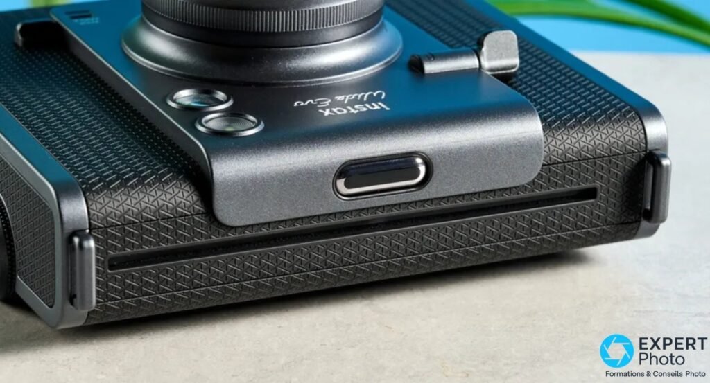 Gros plan sous l'Instax Wide Evo montrant le port USB-C et la fente d'éjection du film Instax Wide en bas du boîtier