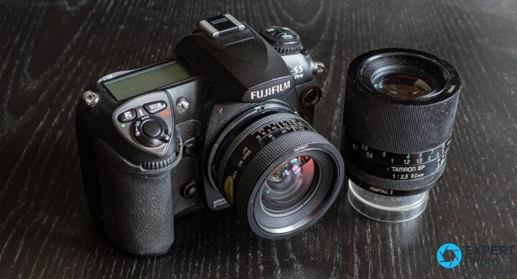 Fujifilm S5 Pro avec un Tamron SP 90mm f/2.5 en monture Adaptall-2 monté, second Tamron SP 90mm posé à côté sur bois.