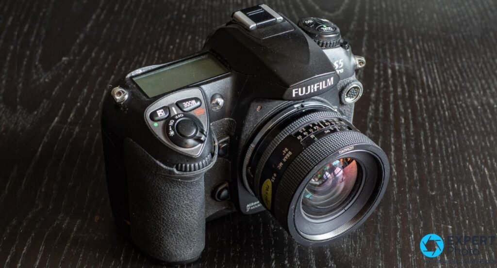 Fujifilm S5 Pro avec Tamron SP 90mm f/2.5 focale fixe macro en Adaptall-2 monté, vue trois-quarts avant sur bois foncé.