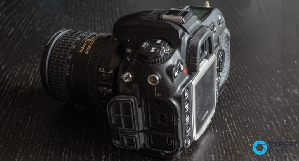 Fujifilm S5 Pro vu du côté gauche, trappes de connectique ouvertes révélant les ports, zoom Nikon AF-S 16-85mm monté.