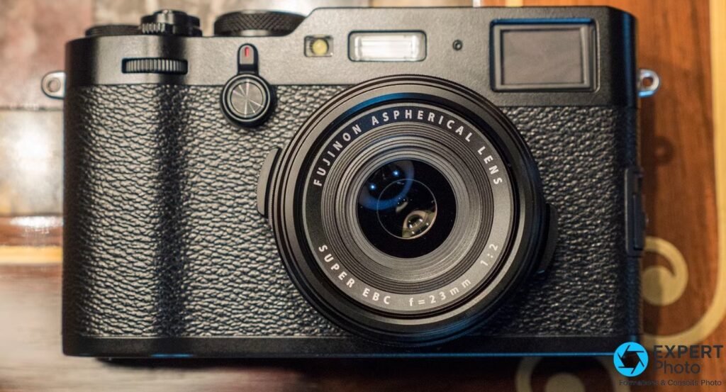 Fujifilm X100F noir de face, gros plan sur l'objectif Fujinon 23 mm f/2 avec bague d'ouverture et flash intégré visibles.