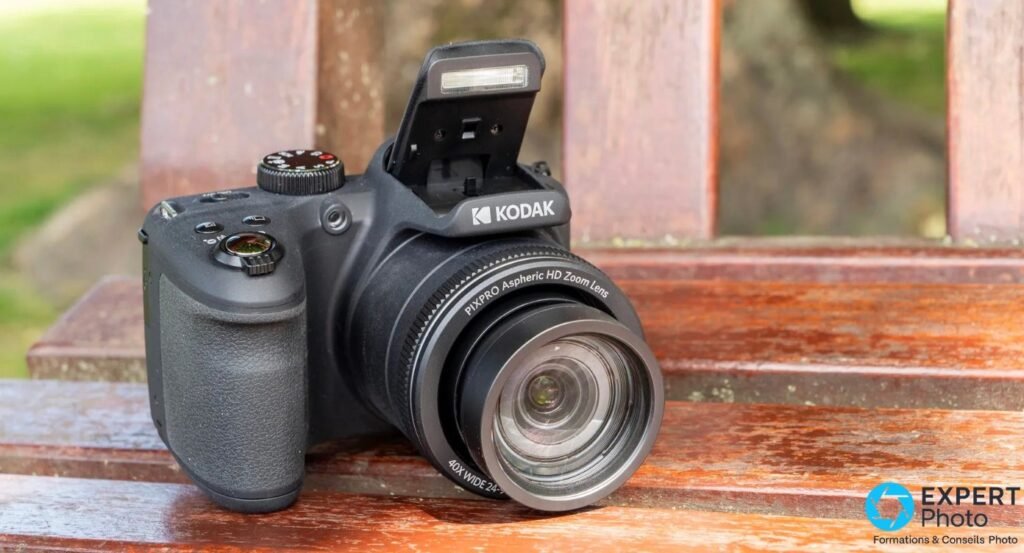 Kodak AZ405 de face, flash relevé, objectif ouvert avec bague PIXPRO Aspheric HD Zoom Lens, posé sur banc bois.