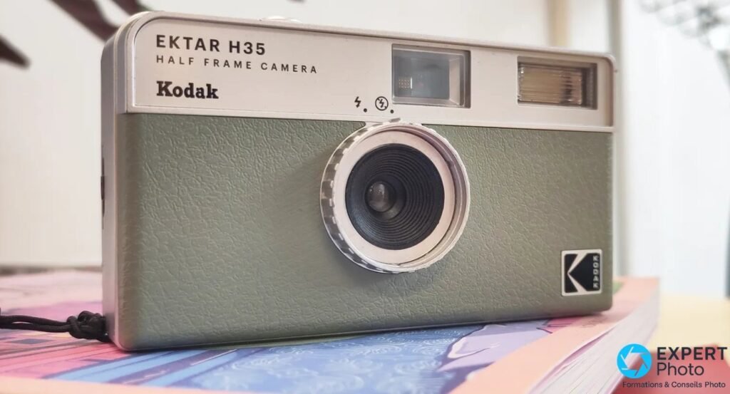 Kodak EKTAR H35 vert sauge posé sur une table blanche entouré de pièces de puzzle roses et bleues, ambiance lifestyle.