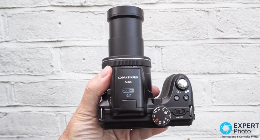 Kodak PIXPRO AZ425 tenu en main, face avant, objectif PIXPRO 42x Wide 24-1008mm, grip texturé noir